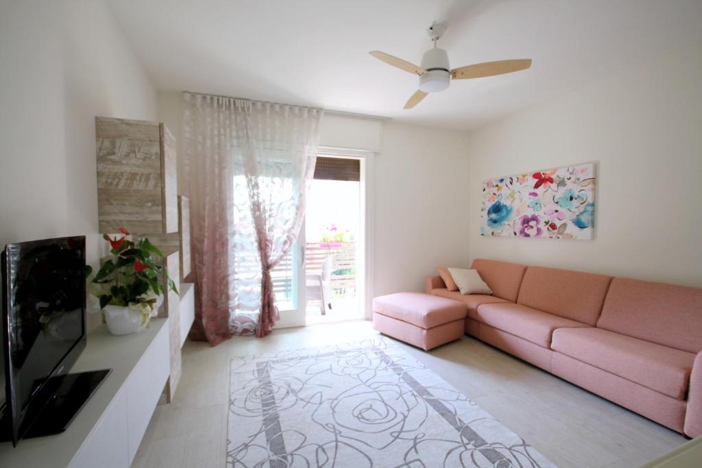 a living room with a pink couch and a tv at La Casa di Eva in Vittorio Veneto