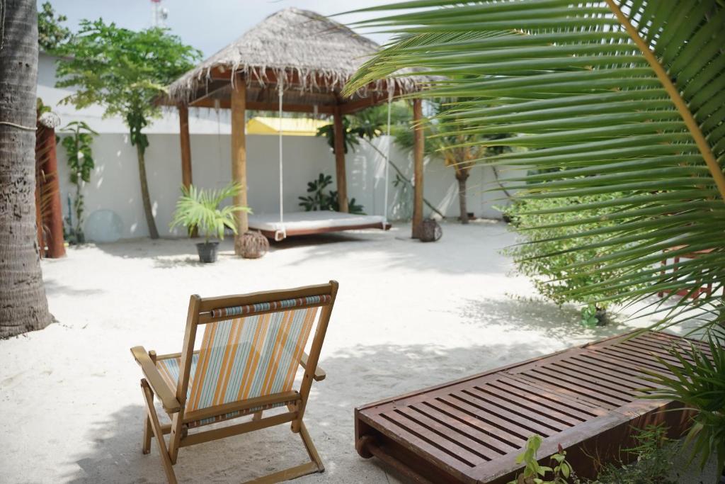 una silla de madera y un banco en un patio en Faima Fishing Lodge at Daravandhoo en Baa Atoll