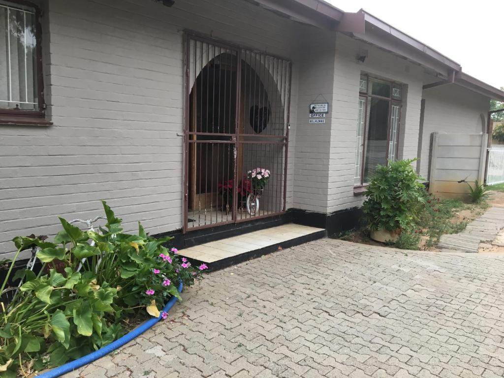 a house with a gate and flowers in front of it at The Lighthouse Guesthouse in Welkom