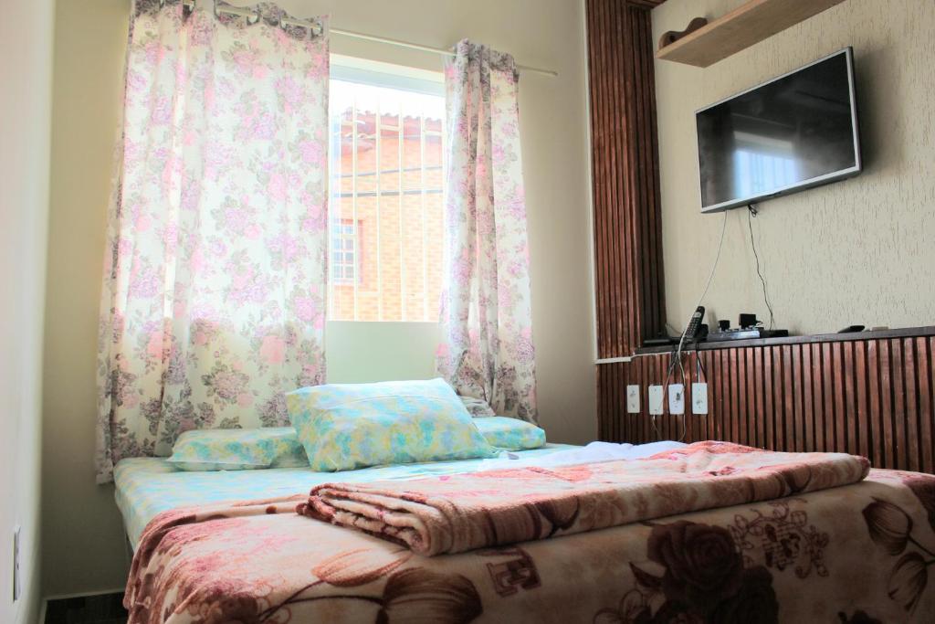 een slaapkamer met een bed en een raam met gordijnen bij Pousada Renascer II in Cachoeira Paulista