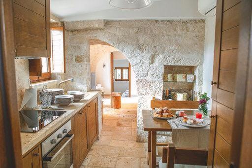 kuchnia z kamienną ścianą ze stołem w obiekcie Trullo Grace -Trulli Anti' Charme & Relax w Alberobello
