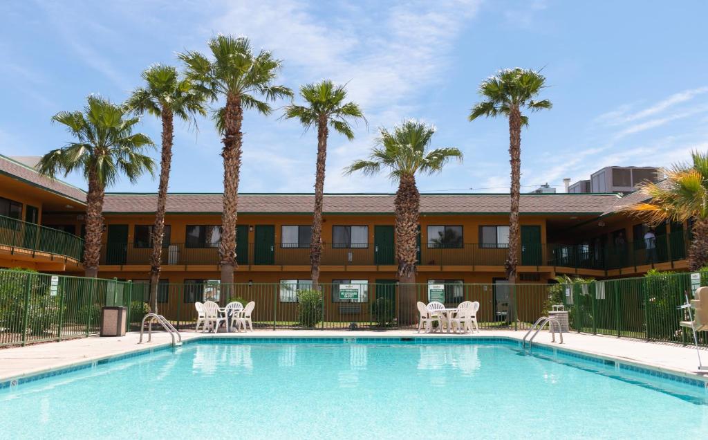 a swimming pool with palm trees in front of a hotel at Budgetel Inn & Suites in Yuma