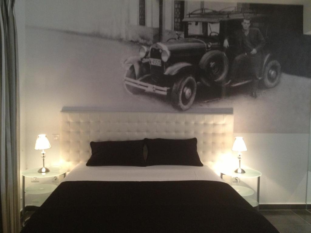 1 dormitorio con 1 cama y una foto de un coche en la pared en Apartamentos Torremenguada, en Torremenga