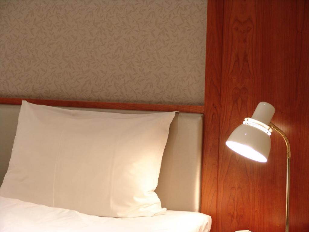 a bed with a white pillow and a lamp at Alver Hotel in Alversund