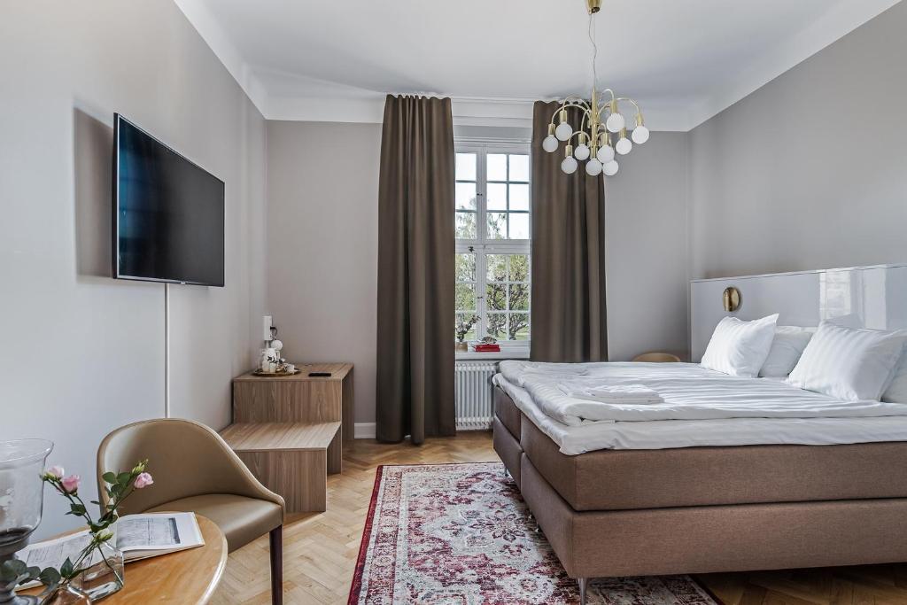 1 dormitorio con cama, mesa y TV en Livgrenadjärmässen Hotell-Fest-Konferens en Linköping