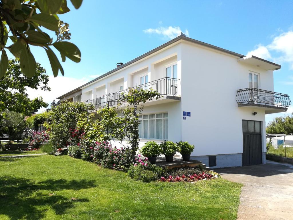 biały budynek z kwiatami na dziedzińcu w obiekcie Apartments Granzola w Sukošanie