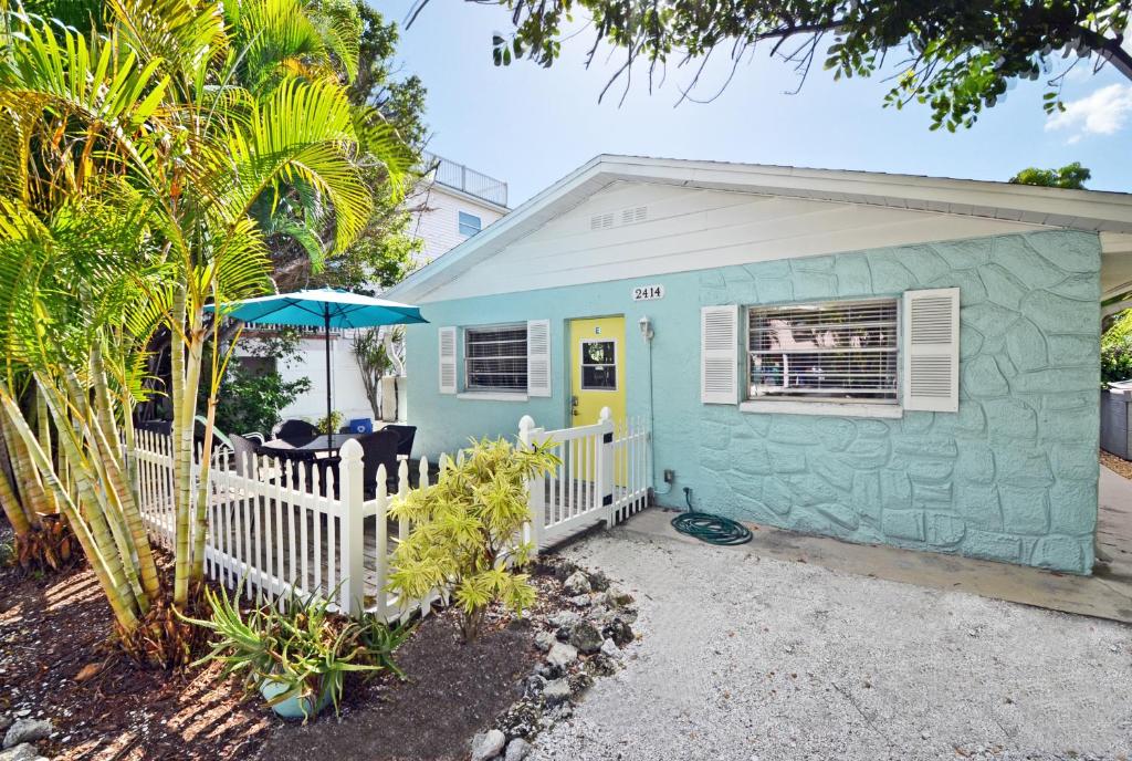 Ce cottage bleu comprend une clôture blanche et un parasol. dans l'établissement Paradise Beach - East 2414, à Bradenton Beach