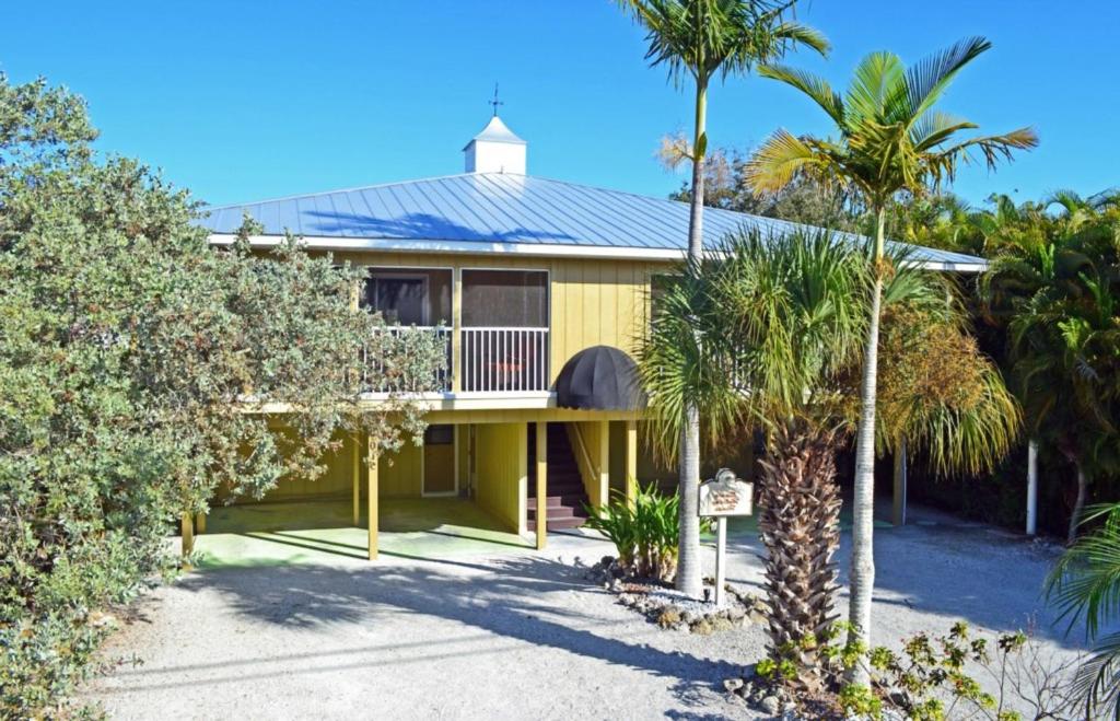 Casa amarilla con porche y palmeras en Crescent Beach 1011 #1, en Sarasota