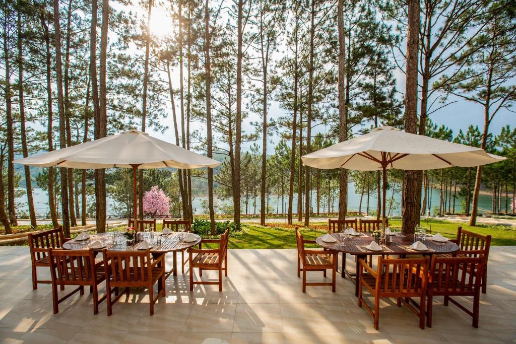 a patio with tables and chairs and umbrellas at CEREJA Hotel & Resort Dalat in Da Lat