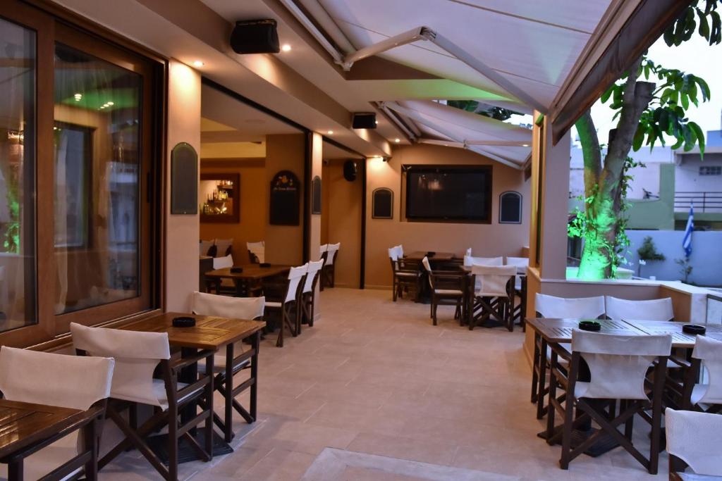 an empty restaurant with wooden tables and chairs at 24 Seven Boutique Hotel in Malia
