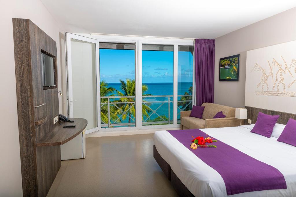 a hotel room with a bed and a view of the ocean at Hotel Beaurivage in Noumea