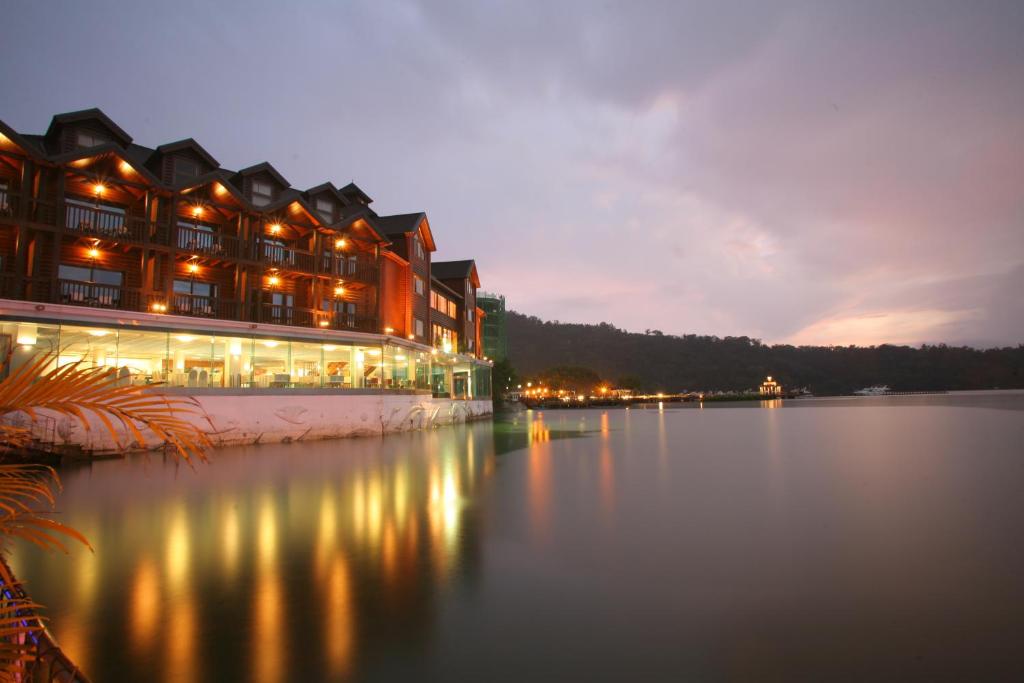 a large building with lights on the water at night at The Richforest Hotel- Sun Moon Lake in Yuchi