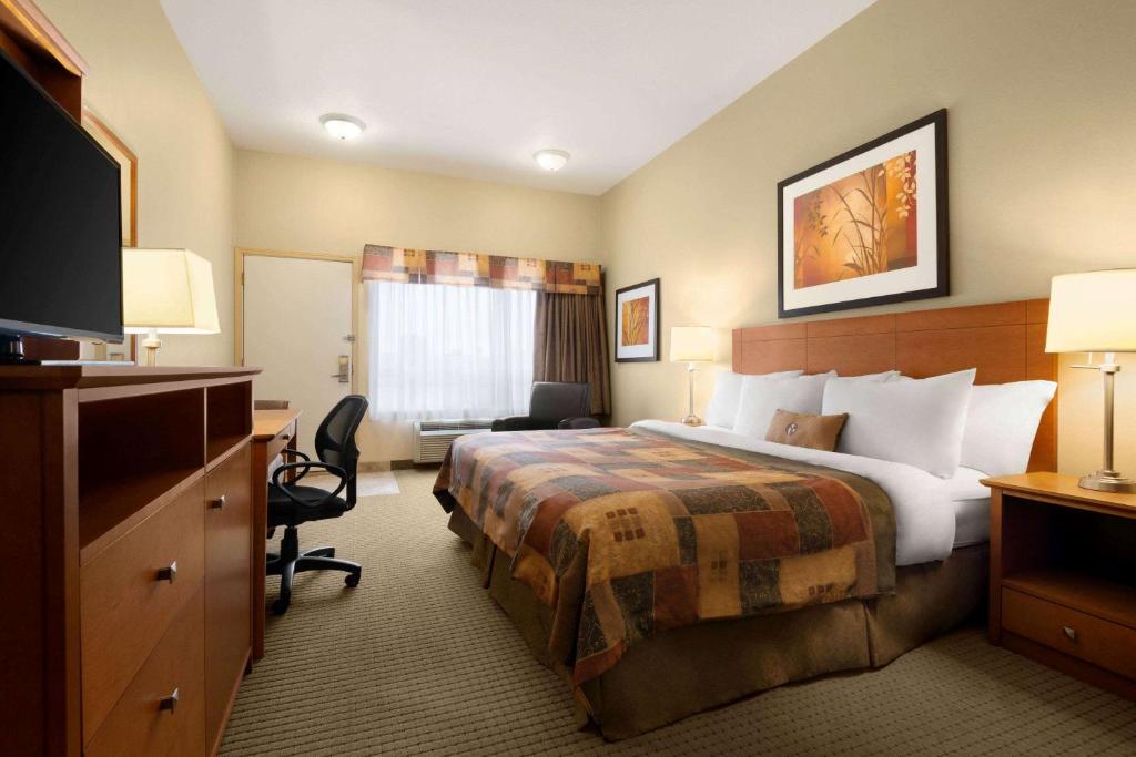a hotel room with a bed and a desk at Ramada by Wyndham Drayton Valley in Drayton Valley