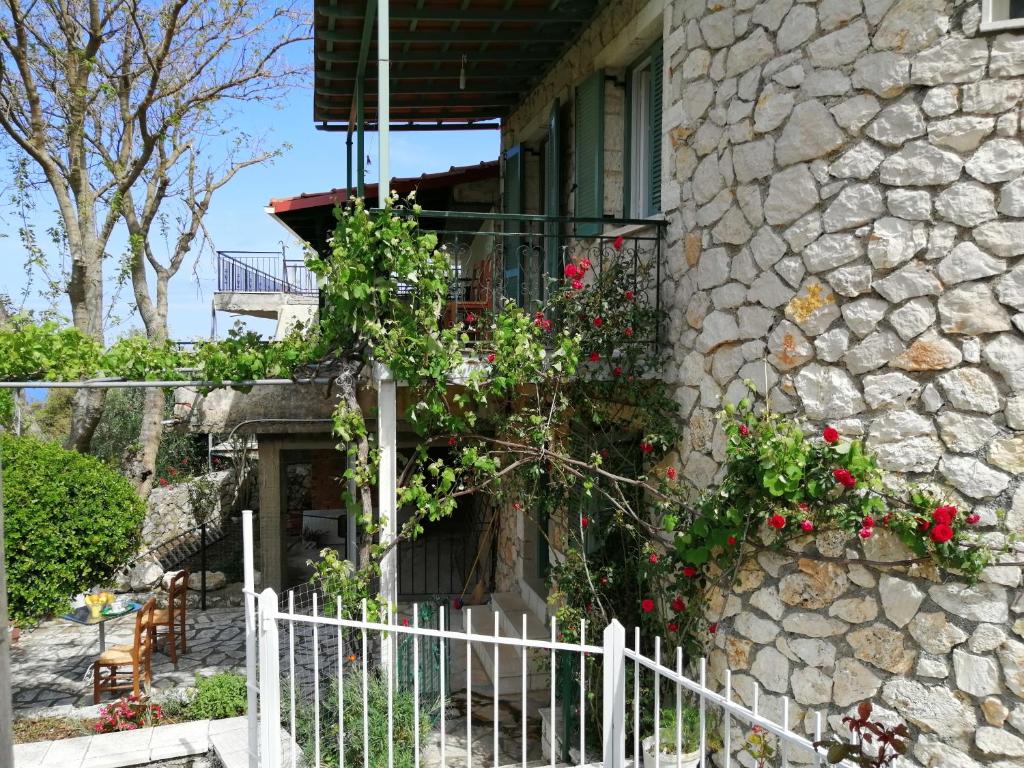 a stone house with a white fence and flowers at Kerkis Traditional Guesthouse in Drymon
