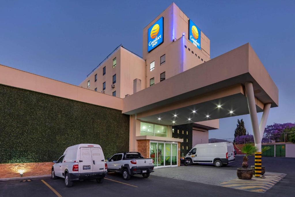 un hotel con dos coches estacionados en un estacionamiento en Comfort Inn Querétaro en Querétaro