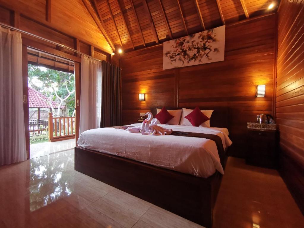 a bedroom with a large bed in a wooden room at Kamasan Cottage in Nusa Penida