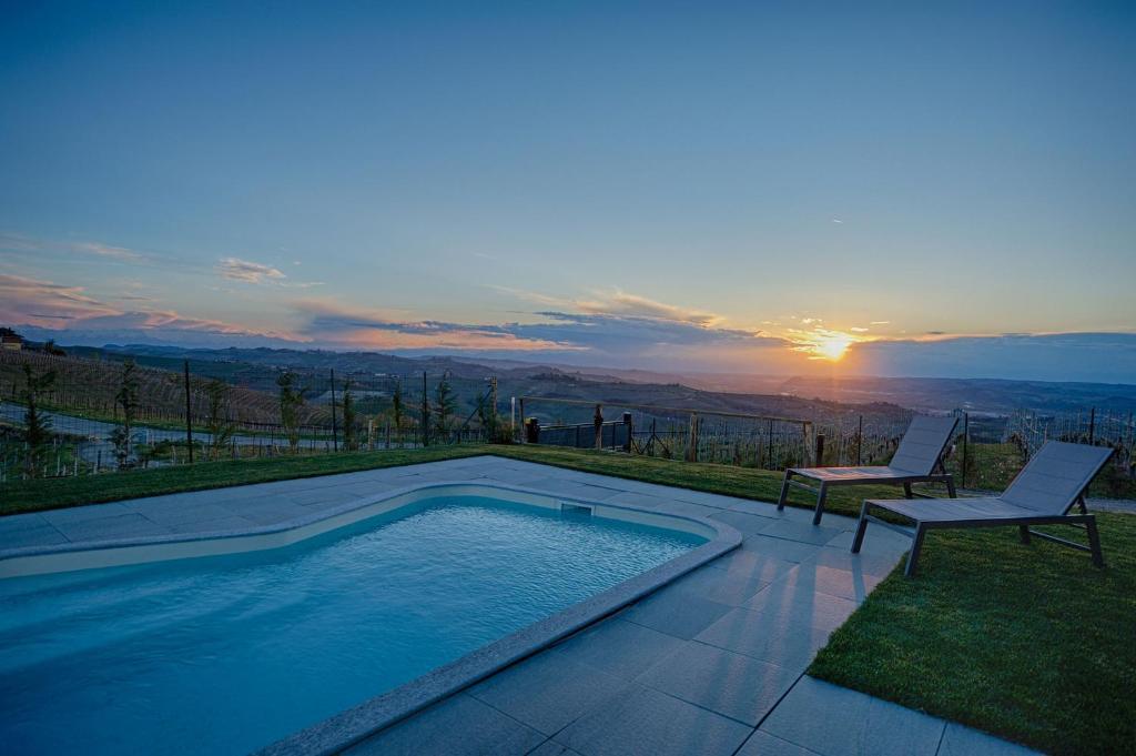 una piscina con due sedie e il tramonto di Ciabot Apartments a Treiso