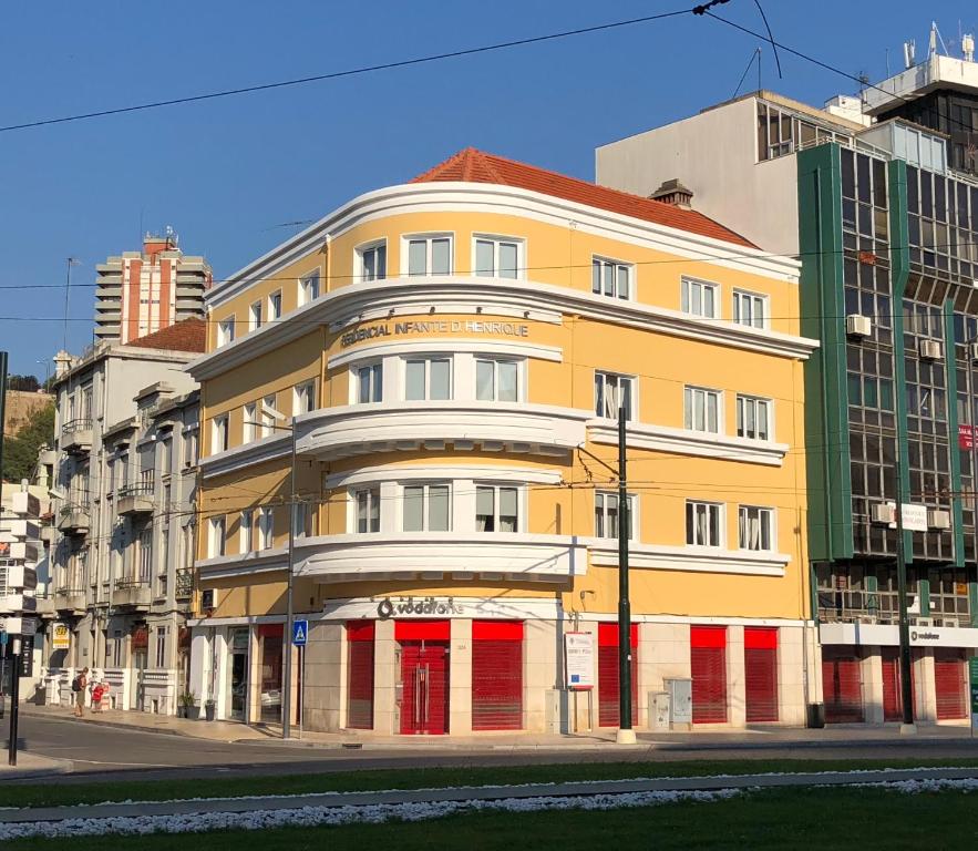 a yellow building with red doors on a street at Guest House Infante Dom Henrique in Coimbra