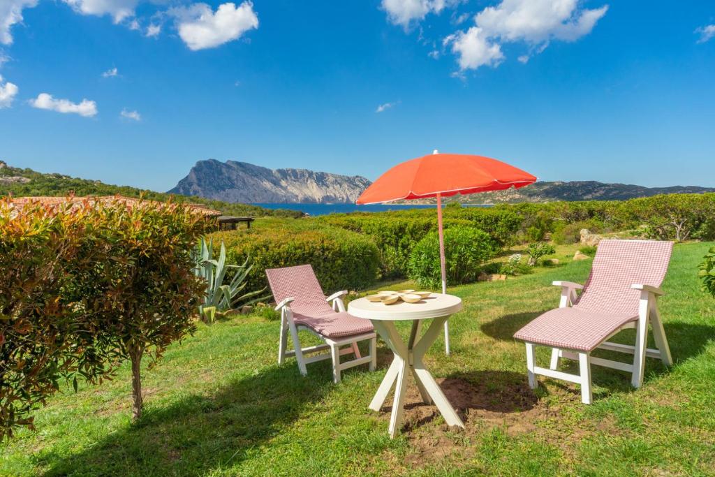 a table with two chairs and an umbrella at coda cavallo villaggio cala paradiso villino C4 in San Teodoro