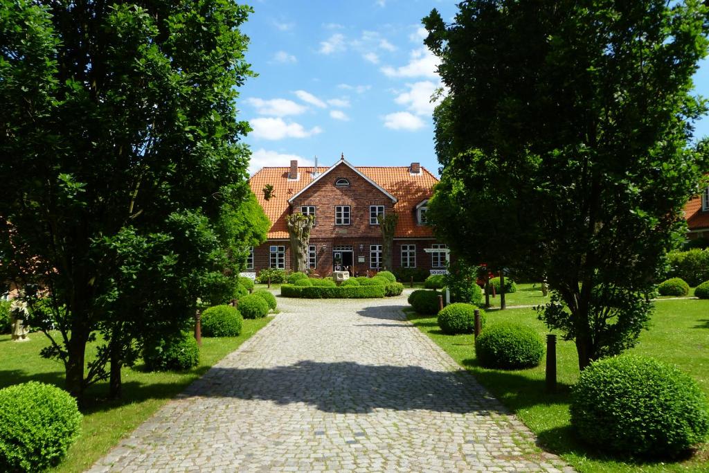 um caminho que leva a uma casa com árvores e arbustos em Friederikenhof Hotel Restaurant & Spa em Lübeck