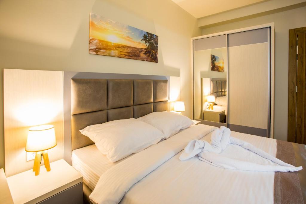 a bedroom with a large white bed with two lamps at Hotel Olimpija plus in Herceg-Novi