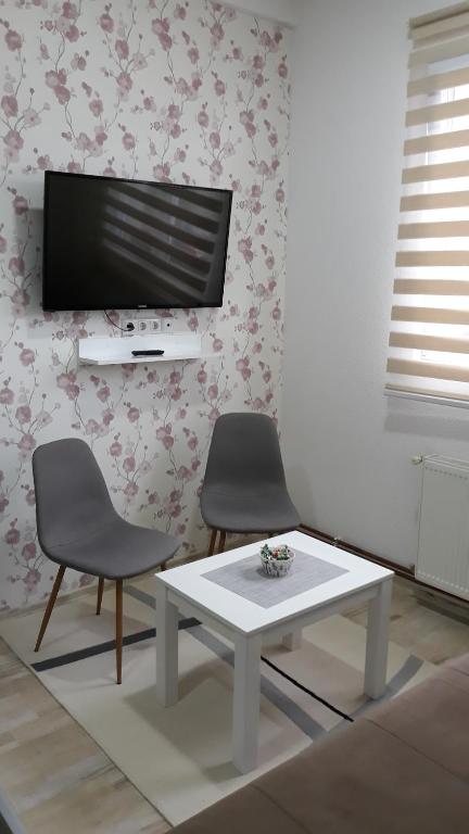 sala de estar con 2 sillas, mesa y TV en AMAI Exclusive, en Tuzla
