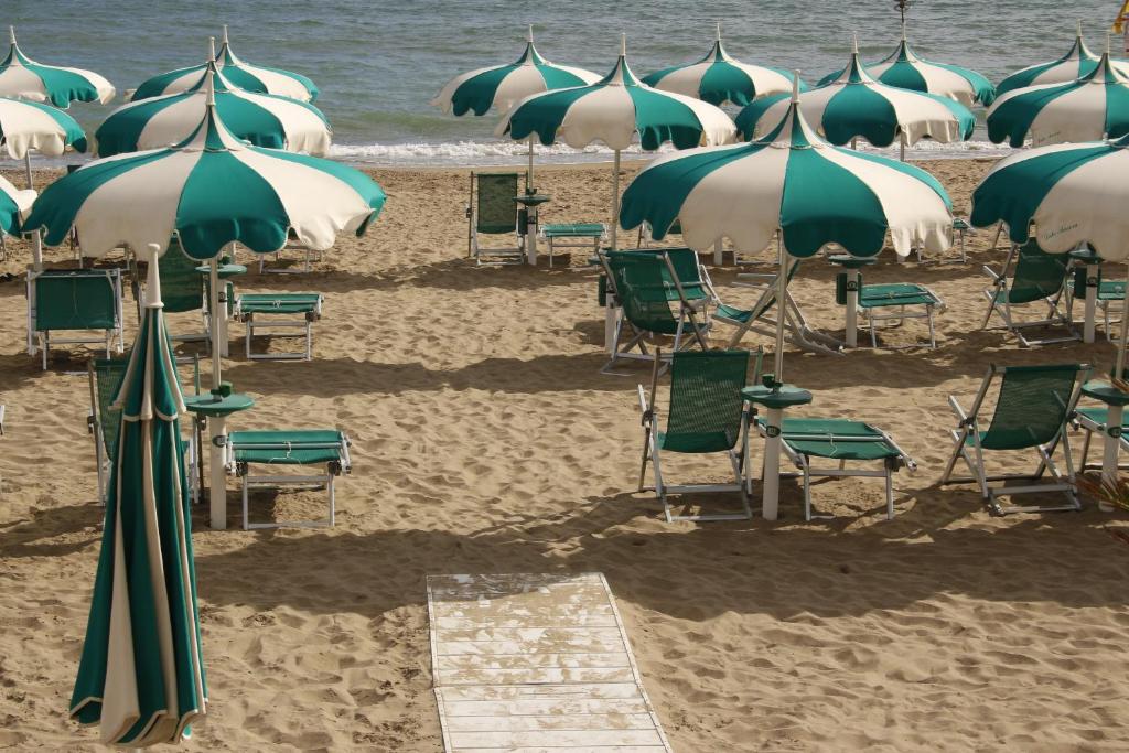een groep stoelen en parasols op een strand bij TERRACINA SEA FRONT FANTASTIC APARTMENT WITH ONE CAR PRIVATE OPEN PARKING in Terracina