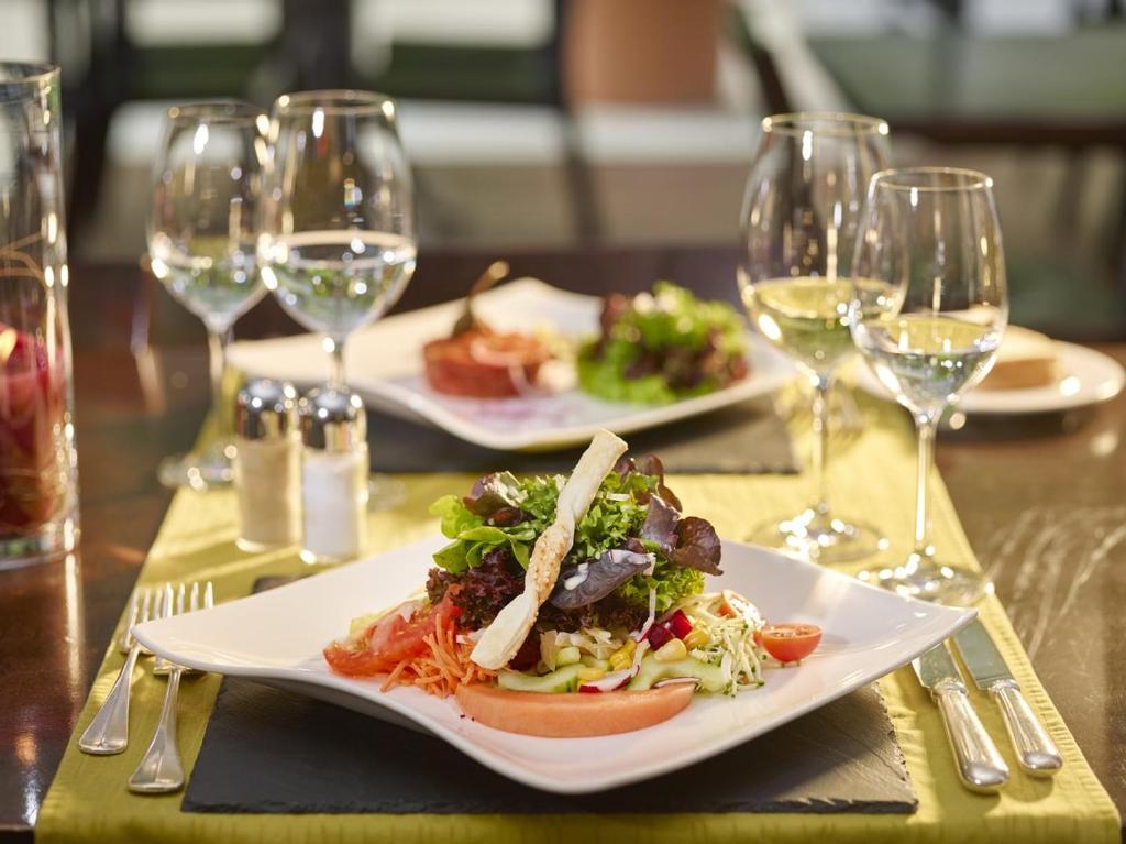 two plates of food on a table with wine glasses at Hotel Tödi in Linthal