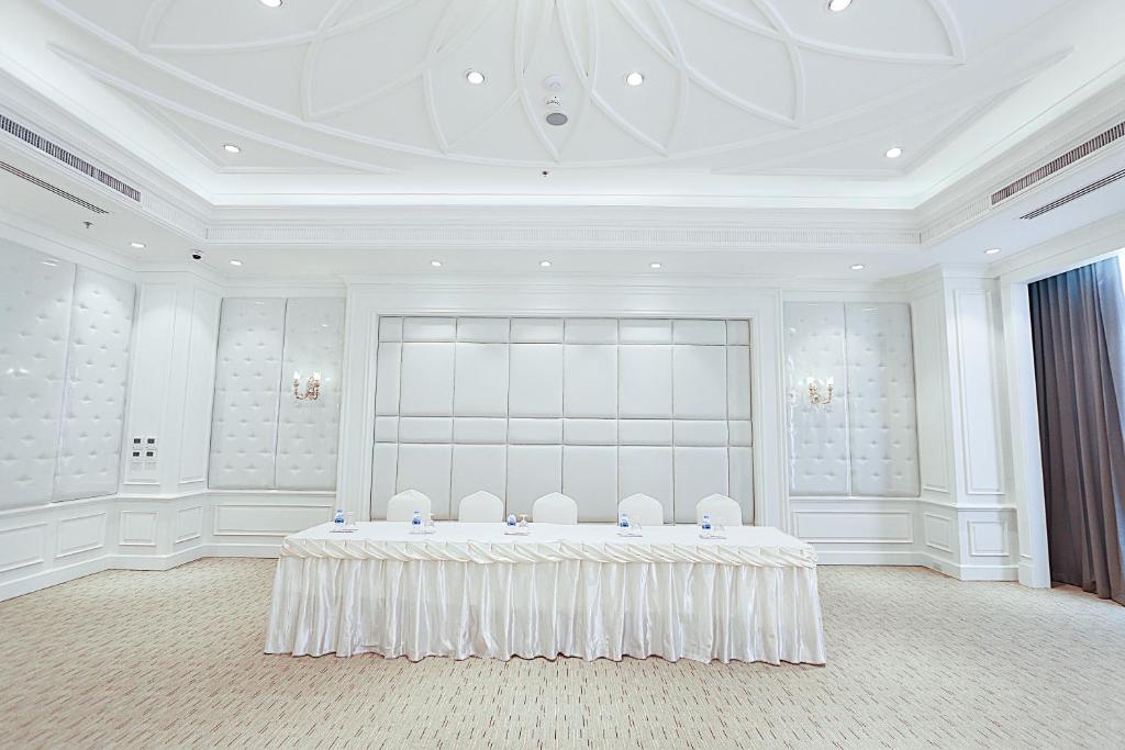 A bright formal meeting room with a head table and open floor space.