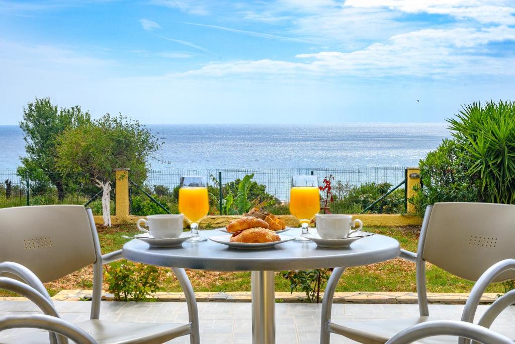 een tafel met een bord eten en uitzicht op de oceaan bij Summer Sun in Skála Kefalonias