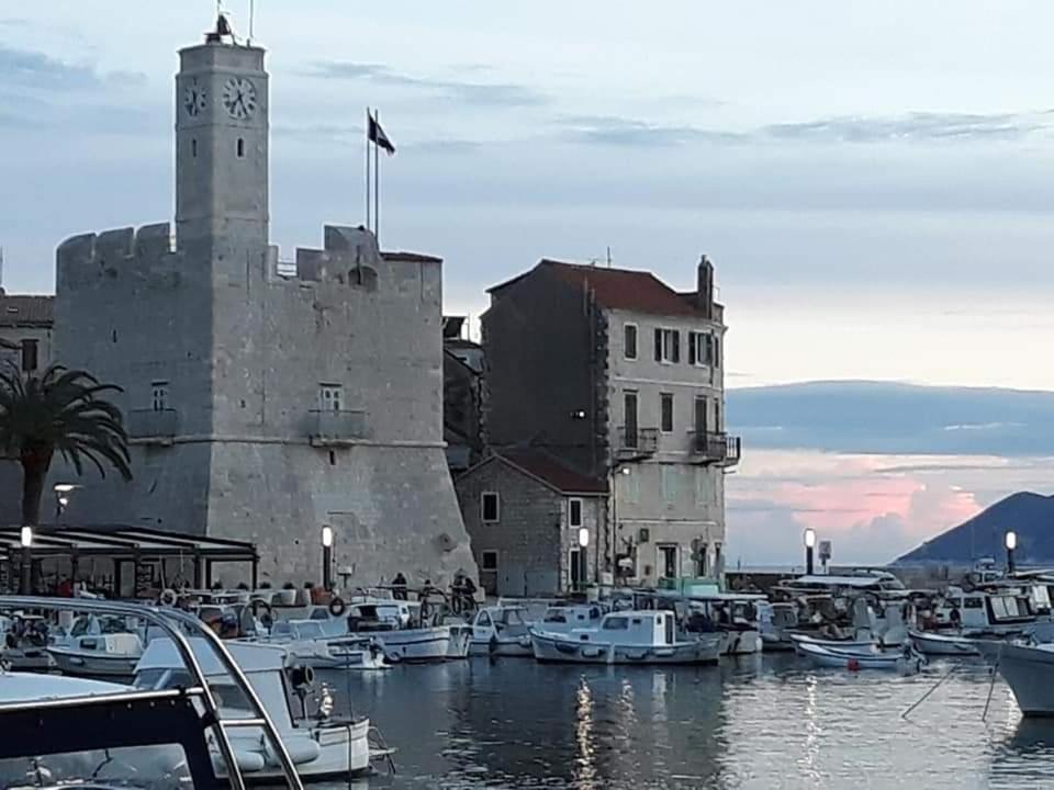 un edificio con torre dell'orologio e barche nell'acqua di Apartment Tina a Komiža