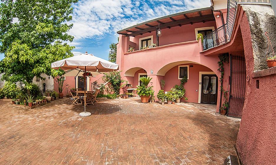 a pink house with an umbrella and a patio at A Corte in Caserta