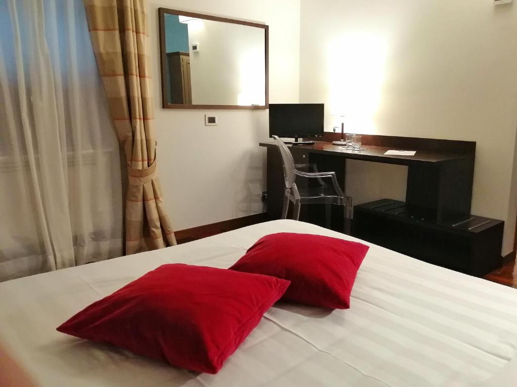 a bedroom with a bed with two red pillows on it at Locanda Giustini in Assisi