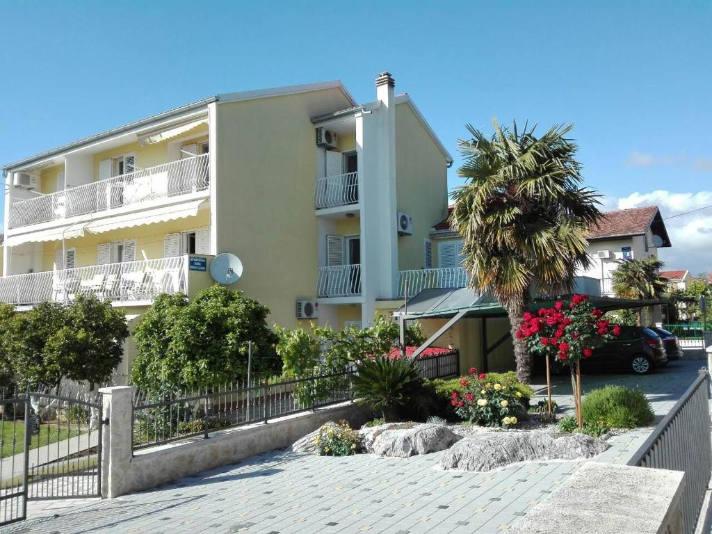 a building with a palm tree in front of it at Apartments Gojka Miocevic in Biograd na Moru