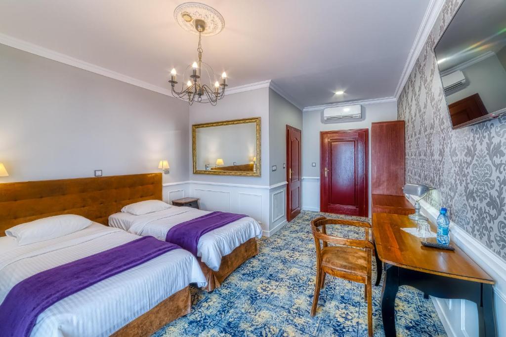 um quarto com 2 camas, uma secretária e uma mesa em Grand Częstochowa em Czestochowa