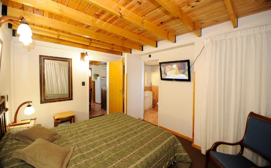 a bedroom with a bed and a tv on the wall at Puente Austral in San Carlos de Bariloche