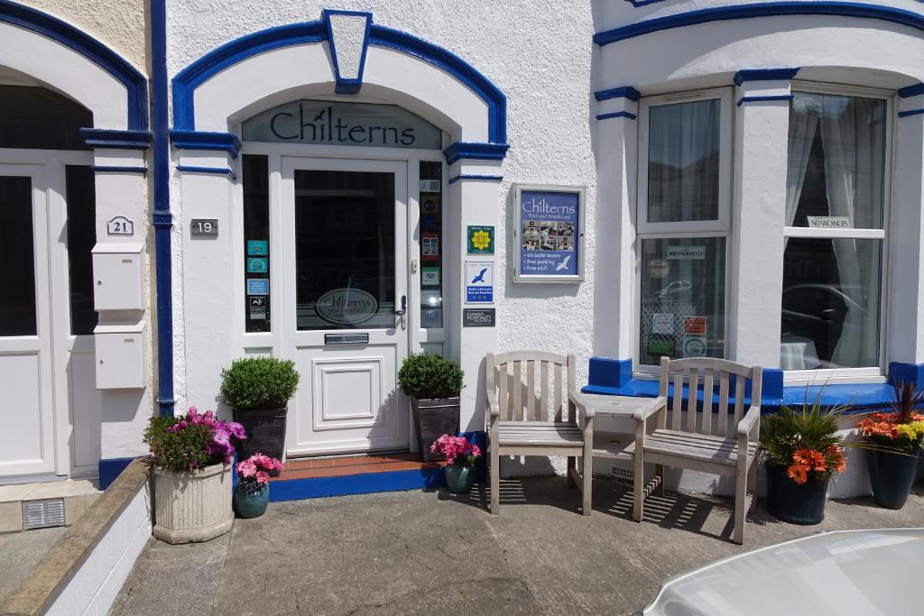 a store with two chairs in front of the door at Chilterns Guest House in Llandudno