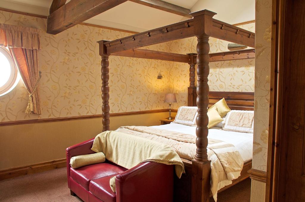 a bedroom with a canopy bed and a red chair at The Dog and Partridge in Langsett