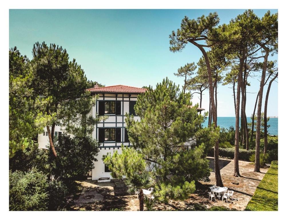 a white house with trees in front of the ocean at Hôtel Ttiki Etchea in Pyla-sur-Mer