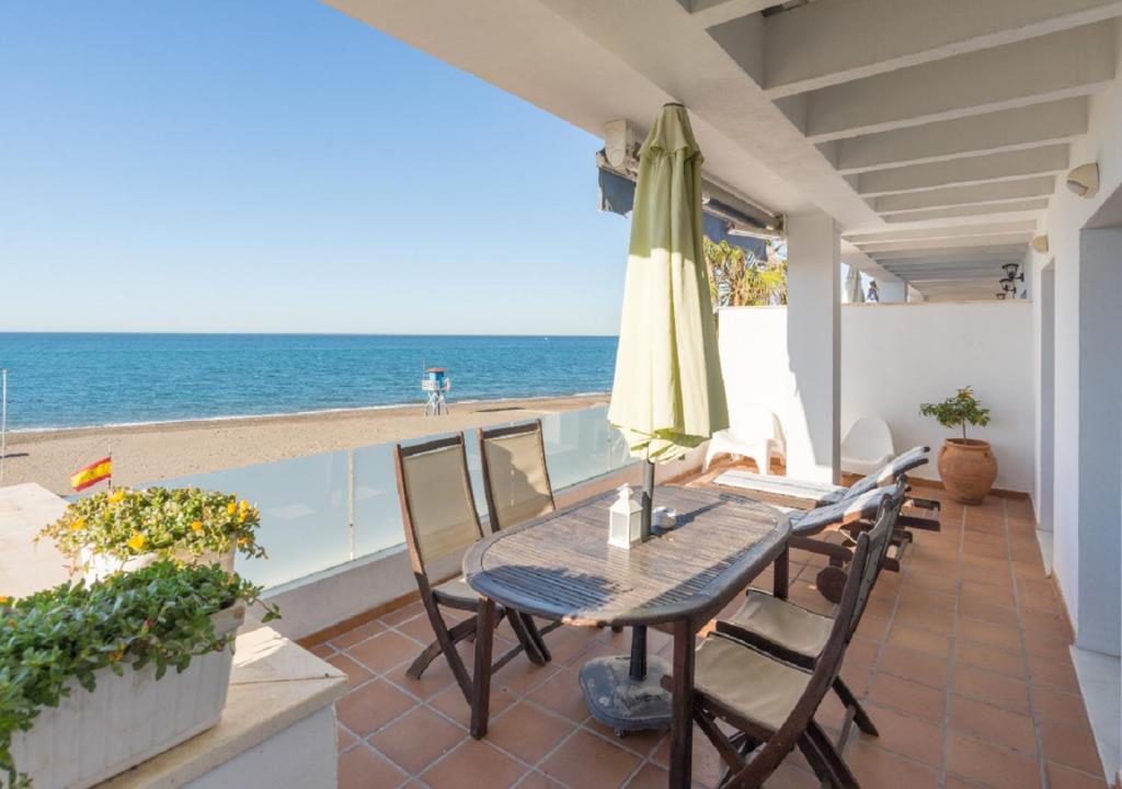 a patio with a table and an umbrella and the beach at Apartamentos Varadero Sea View in Cala del Moral