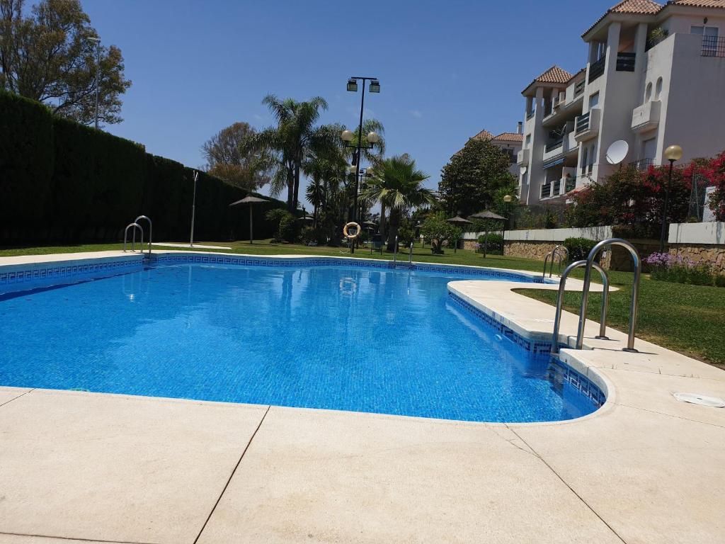 a large blue swimming pool in front of a building at APARTAMENTO PUERTO BANUS/PLAYA in Marbella