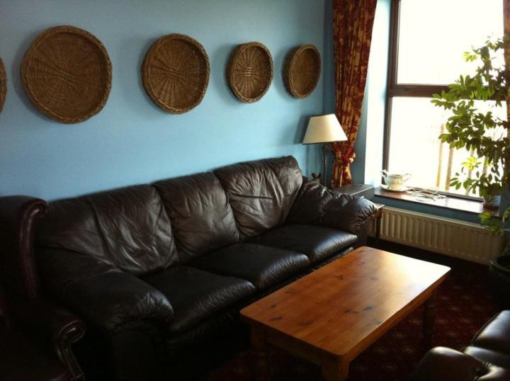 a living room with a leather couch and a wooden table at Pier House Bed & Breakfast in Inis Mor