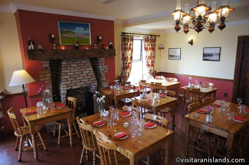 a dining room with wooden tables and a fireplace at Pier House Bed & Breakfast in Inis Mor