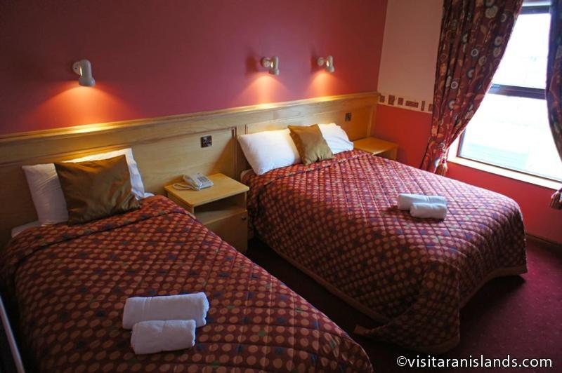 two beds in a hotel room with red walls at Pier House Bed & Breakfast in Inis Mor