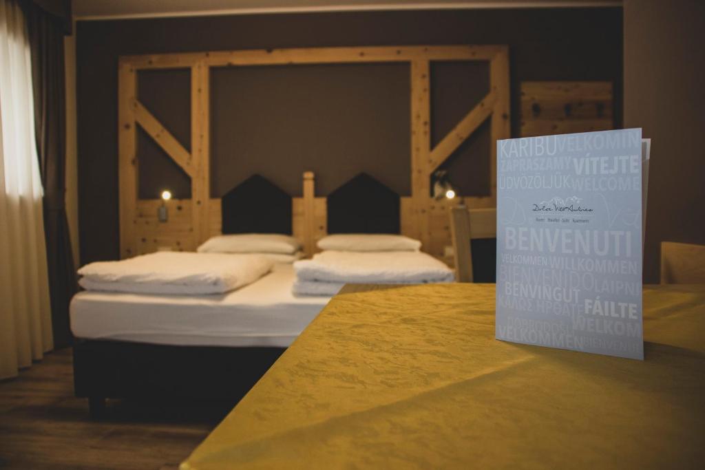 2 camas en una habitación con un cartel en una mesa en DolceVita Ambiez B&B en San Lorenzo in Banale