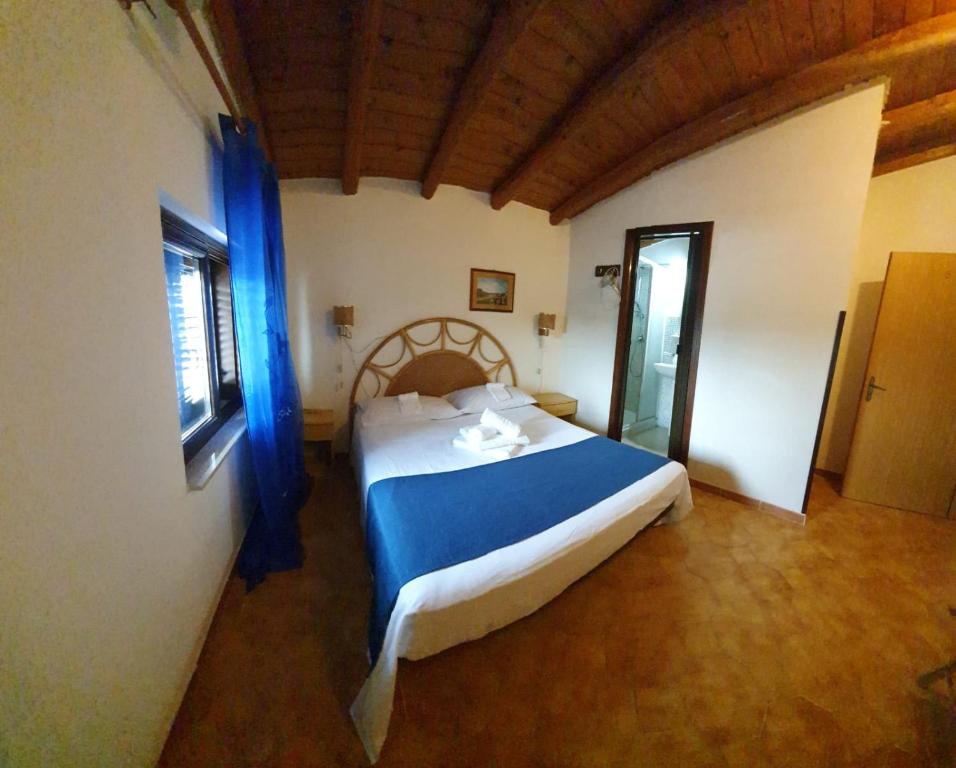 Un dormitorio con una cama con sábanas azules y una ventana. en Beb Eclissi, en Fontane Bianche
