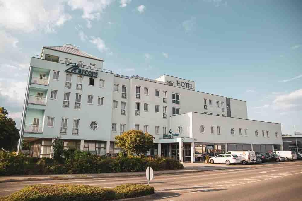 un grand bâtiment blanc avec des voitures garées dans un parking dans l'établissement Hotel am Südtor, à Backnang