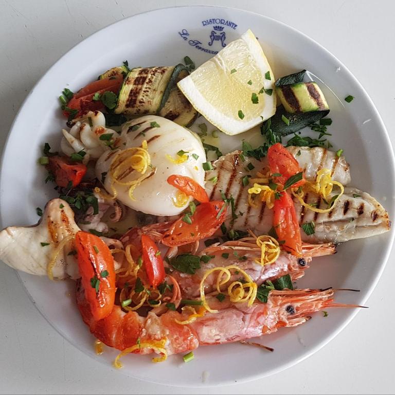 a white plate of food with shrimp and vegetables at Hotel Villa Principe in San Nicola Arcella