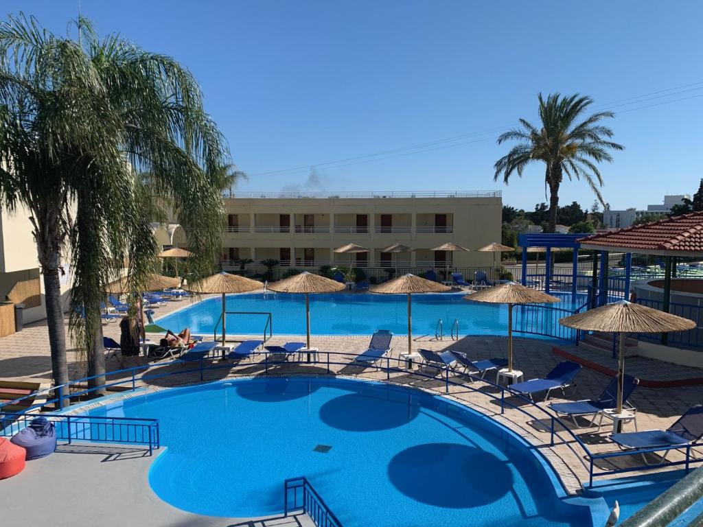 a large swimming pool with chairs and umbrellas at Romantza Mare in Kallithea Rhodes