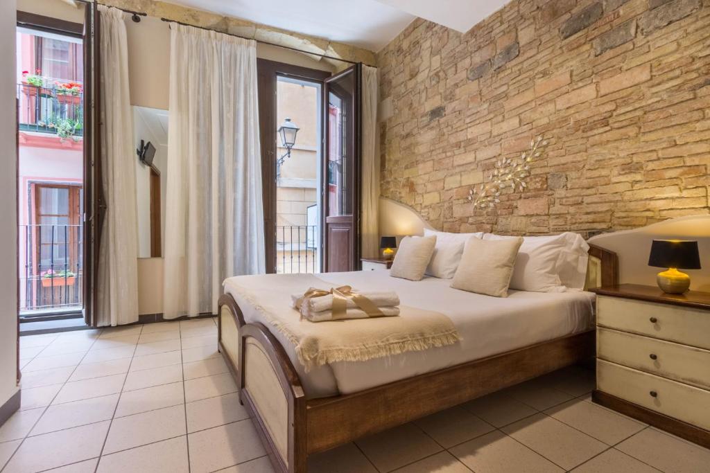 a bedroom with a large bed and a brick wall at Arcobaleno Rooms in Cagliari